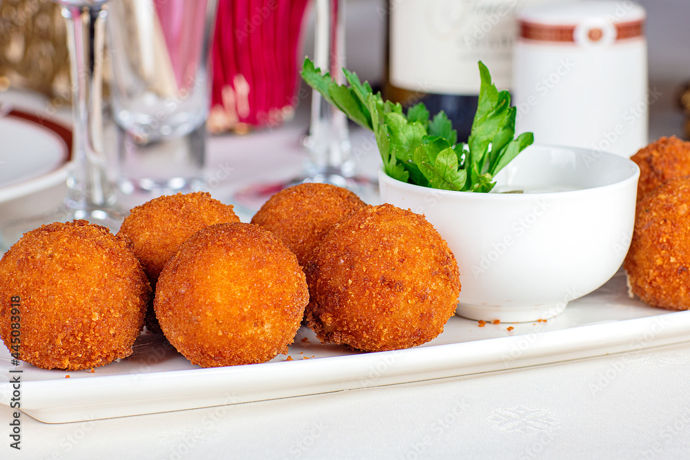 Meat balls fried with cheese filling, close-up, on a plate. Near the wine glasses and a bottle of wine and napkins. Meat balls fried with cheese filling, close-up, on a plate. Near the wine glasses and a bottle of wine and napkins.