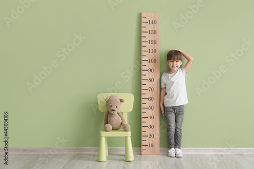 Little boy measuring height near color wall photo