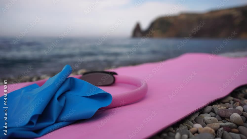 Young woman with black hair, fitness instructor in leggings and tops doing stretching and pilates on yoga mat near the sea. Female fitness yoga routine concept Healthy lifestyle harmony and meditation