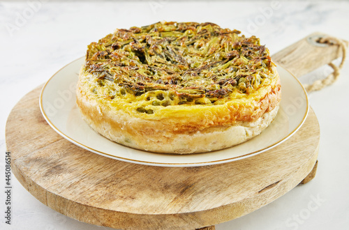 Pie with asparagus and peas on plate and wooden stand. Step by step recipe