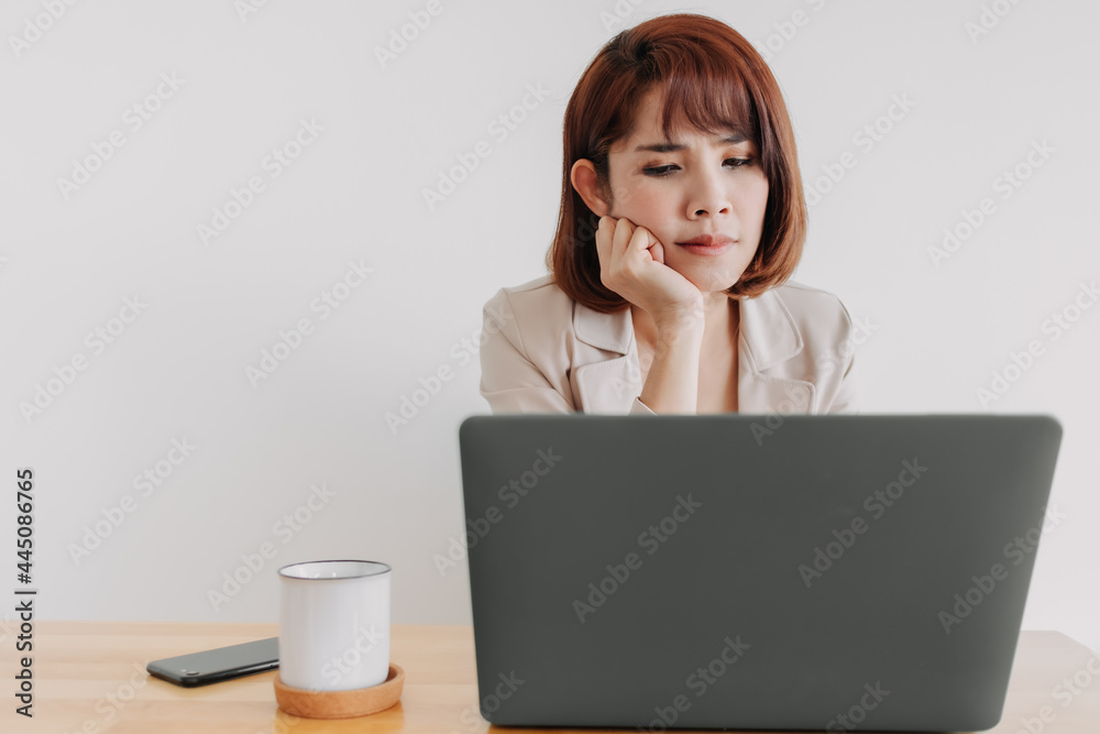 Asian working woman is using laptop on the office desk with white background. Asian working woman is using laptop on the office desk with white background.