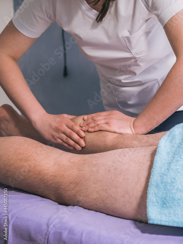 two people, physiotherapist massaging man's leg muscles - calves.