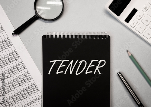 Word tender on office desk with stationery stuff. Business concept photo