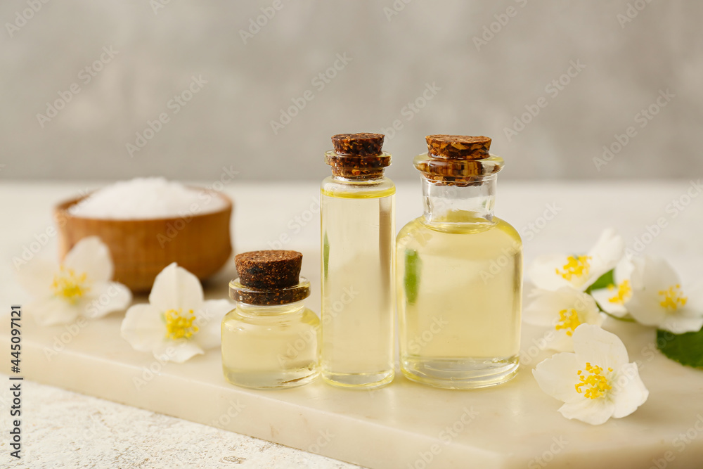 Bottles of essential oil, sea salt and jasmine flowers on table Bottles of essential oil, sea salt and jasmine flowers on table