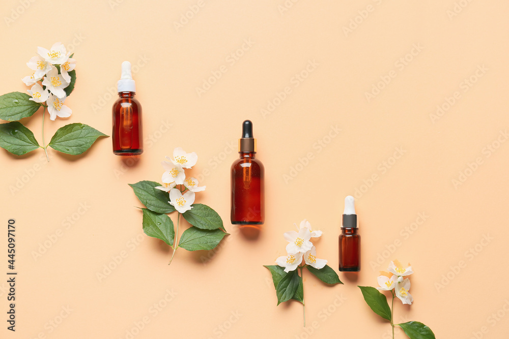 Bottles of essential oil and jasmine flowers on color background