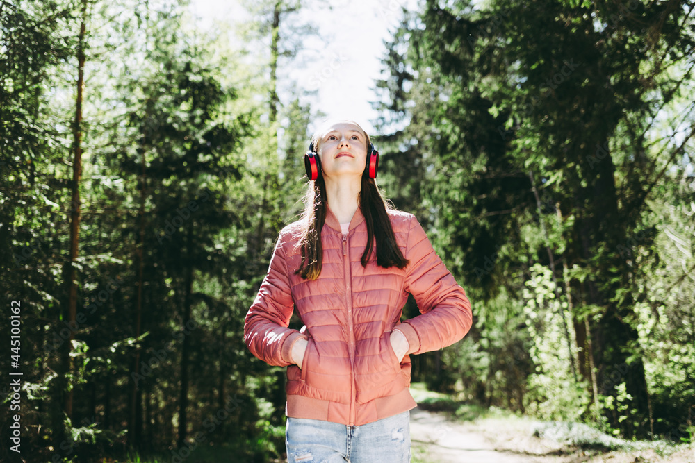 One lovely slim fit thin teen girl enjoying, listening to music in the forest while walking spring day forest or park. One lovely slim fit thin teen girl enjoying, listening to music in the forest while walking spring day forest or park.