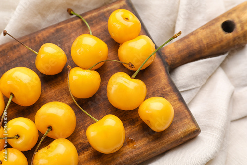 Board with tasty sweet cherries on light fabric background