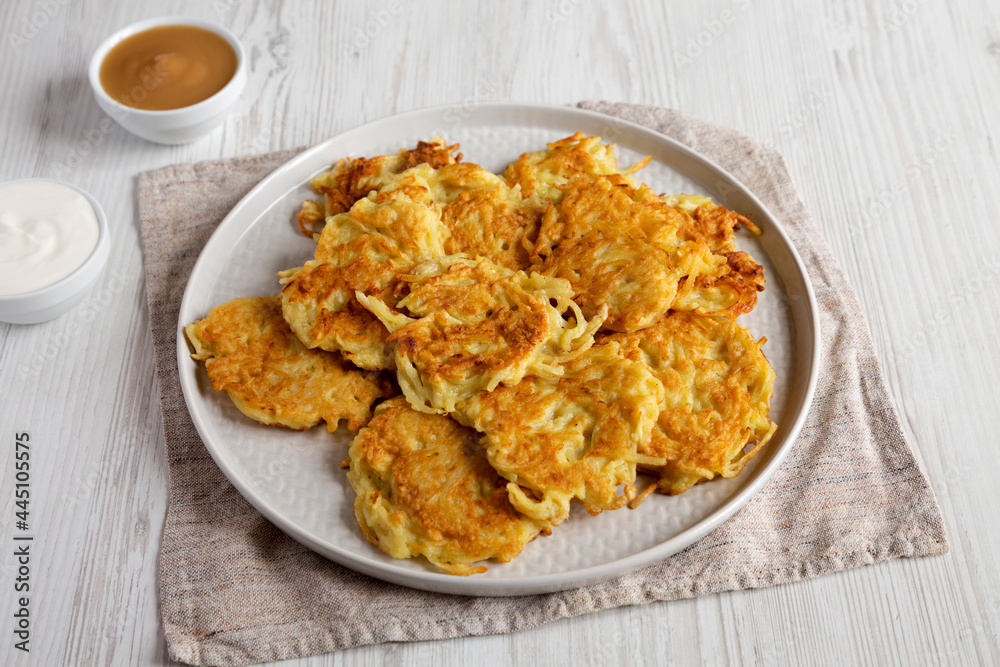 Homemade Potato Pancakes Latkes with Apple Sauce and Sour Cream on a white wooden background, side view. Homemade Potato Pancakes Latkes with Apple Sauce and Sour Cream on a white wooden background, side view.