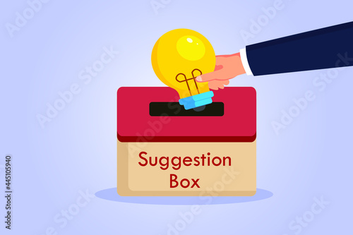 Suggestion vector concept. Hand putting a light bulb into a suggestion box photo