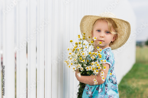 Portrait of a little girl in a straw hat with a bouquet of daisies photo