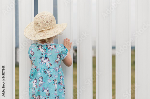 Cute little girl looking at something through fence
