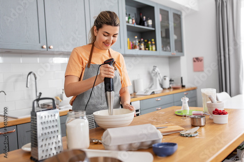 Fotografie culinary, baking and people concept - happy smiling young woman cooking food on