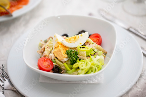 A light appetizer salad of greens, eggs and boiled meat in a small plate on the table.
