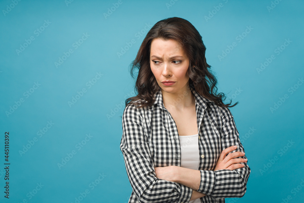 Portrait of an angry young woman standing over isolated blue background. Portrait of an angry young woman standing over isolated blue background.