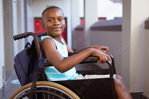 Foto Portrait of smiling disabled african american schoolboy sitting in wheelchair in