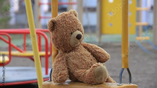 Forgotten Teddy Bear on a Childrens Swing in an Empty Playground. Concept Childhood, Psychology, Family Relations, Foster Child, Kindergarten, Orphanage