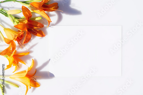 Mockup poster or flyer for presentation, stationery and yellow lilies flowers with hard shadows on a gray background in a elegant modern minimalist style. Congratulations blank or invitation