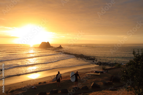 Surfers at sunrise in Mangawhai New Zealand photo