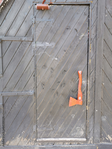 A brown wooden door with a handle in the form of a red axe in a cafe located in the stone wall of the Vyborg Castle in the city of Vyborg