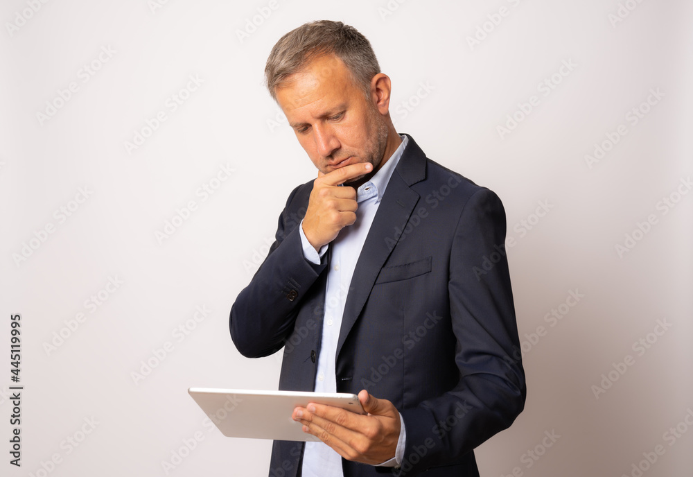 Pensive young businessman using digital tablet isolated on white background Pensive young businessman using digital tablet isolated on white background