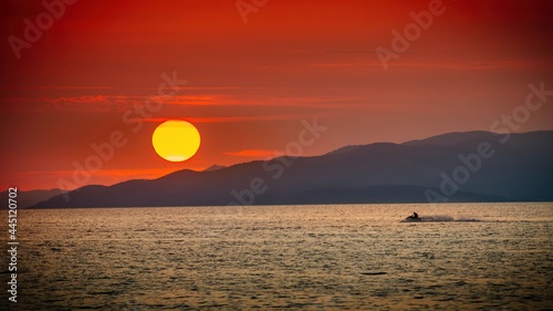 Pływający ludzie na morzu na tle ogromnego zachodzącego słońca © Michal45