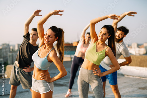 Fitness, sport, friendship and healthy lifestyle concept. Group of happy people exercising outdoor.