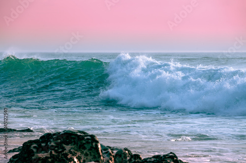 The wave rolls over the rocky shore