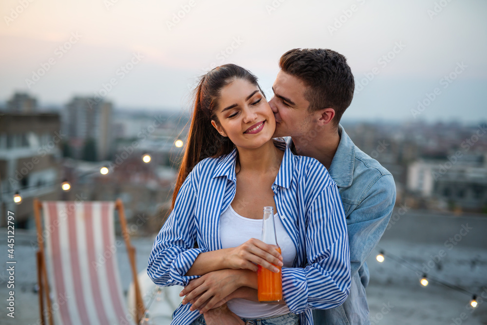 Young couple in love having fun at rooftop party in sunset.