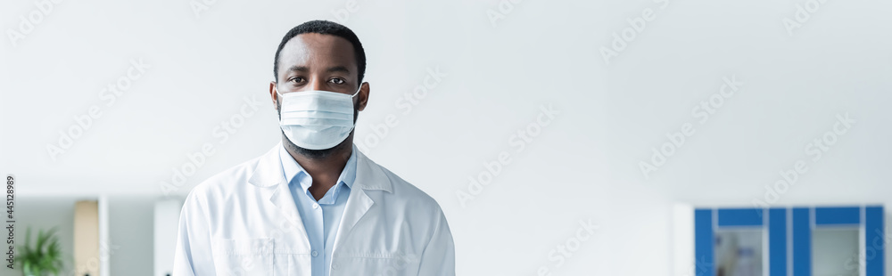African american doctor in medical mask standing in clinic, banner African american doctor in medical mask standing in clinic, banner