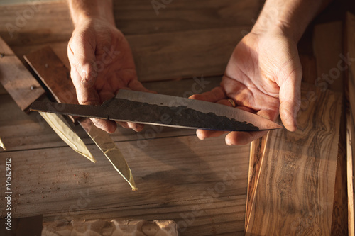 Hands of caucasian male knife maker in workshop, holding handmade knife photo