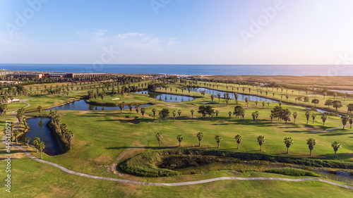 Green golf courses by the sea. Salgados beach. Portugal, Albufeira. Aerial view and high trees, sunny day  photo