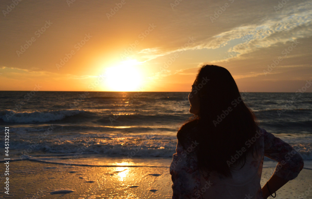 Silhouette of a girl watching sunset on the shore of Naples in South Florida, USA
