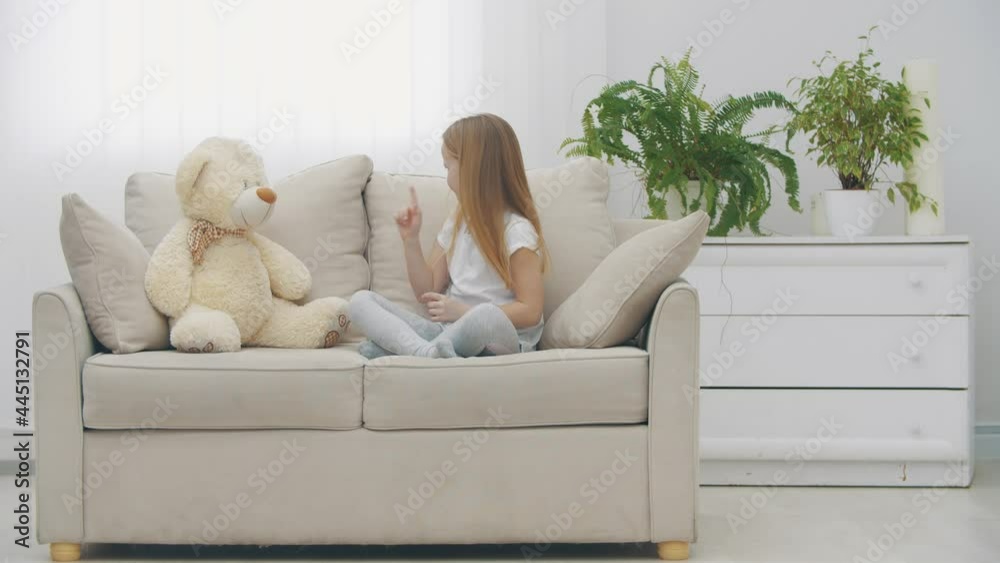 4k slowmotion video of sad little blond girl in white clothes near teddy bear. 4k slowmotion video of sad little blond girl in white clothes near teddy bear.