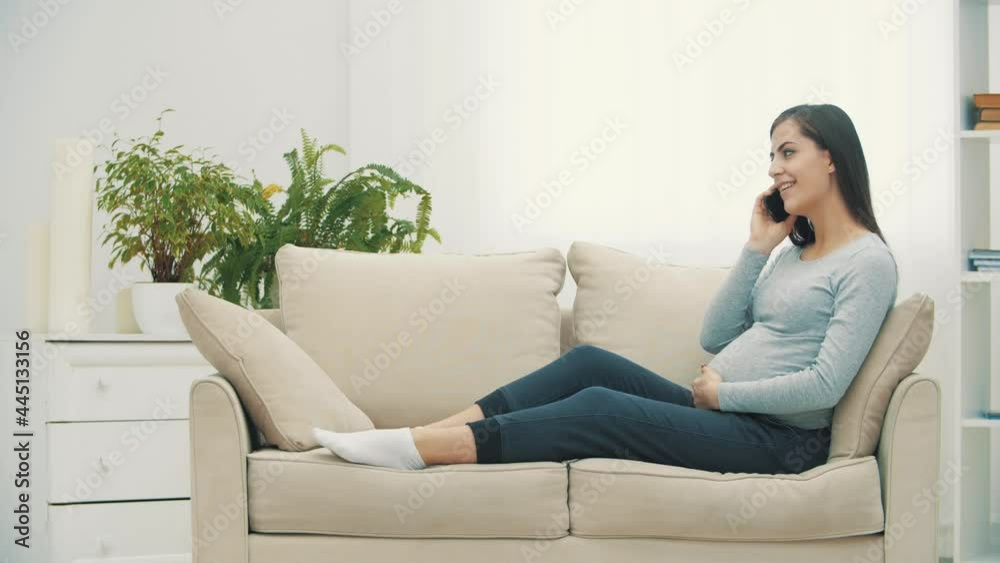 4k slowmotion video of pregnant woman on sofa talking over the phone. 4k slowmotion video of pregnant woman on sofa talking over the phone.