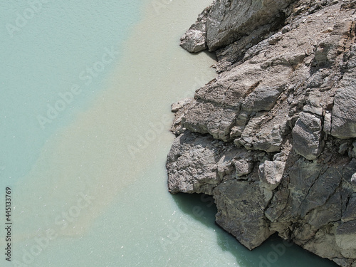 Water edge of Lac de Moiry with rocky shore. Lac de Moiry is a reservoir in the municipality of Grimentz in the Swiss Alpine valley 