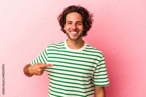 Young caucasian man isolated on pink bakcground person pointing by hand to a shirt copy space, proud and confident