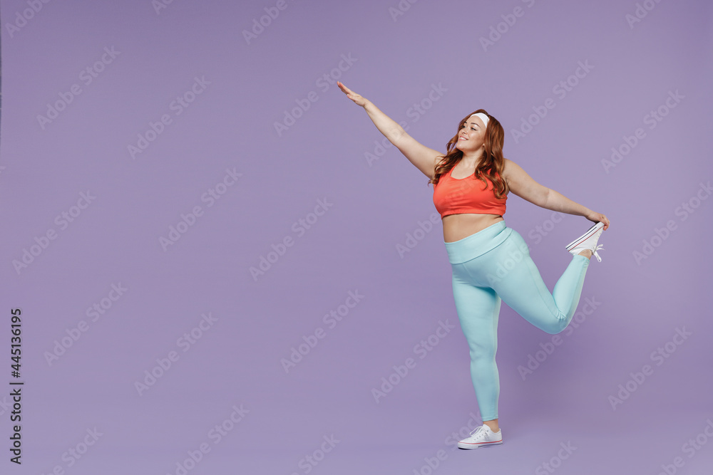Full length side view young chubby overweight plus size big fat fit woman wear red top warm up training do legs stretch exercise isolated on purple background gym. Workout sport motivation concept
