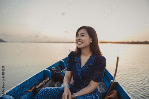 A girl is smiling on the boat sailing in the sea during sunrise