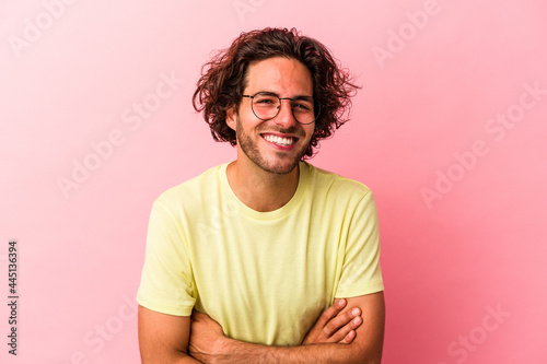 Young caucasian man isolated on pink bakcground laughing and having fun.
