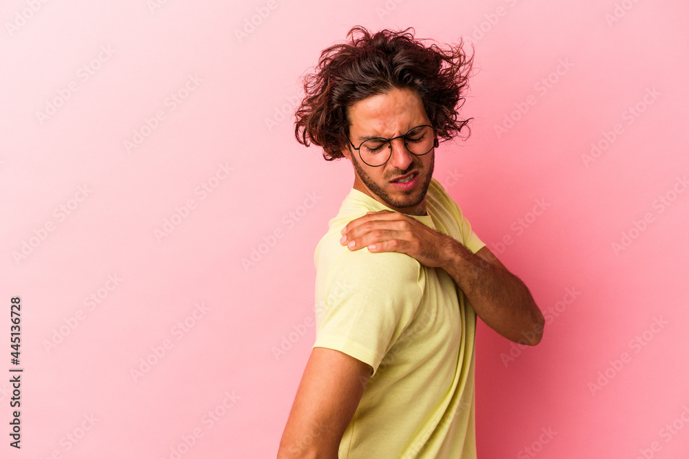 Young caucasian man isolated on pink bakcground having a shoulder pain. Young caucasian man isolated on pink bakcground having a shoulder pain.