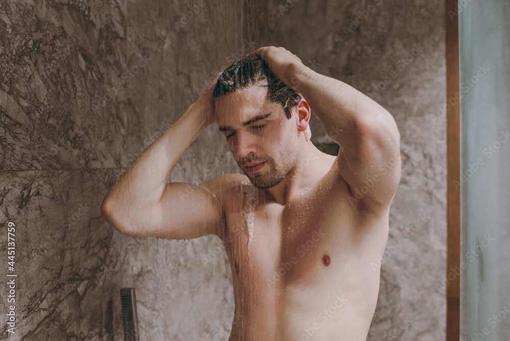 Young handsome half naked topless relaxed brunette caucasian man 20s taking hot shower washing hair close eyes indoors in bathroom at home. People healthcare daily morning routine lifestyle concept Young handsome half naked topless relaxed brunette caucasian man 20s taking hot shower washing hair close eyes indoors in bathroom at home. People healthcare daily morning routine lifestyle concept