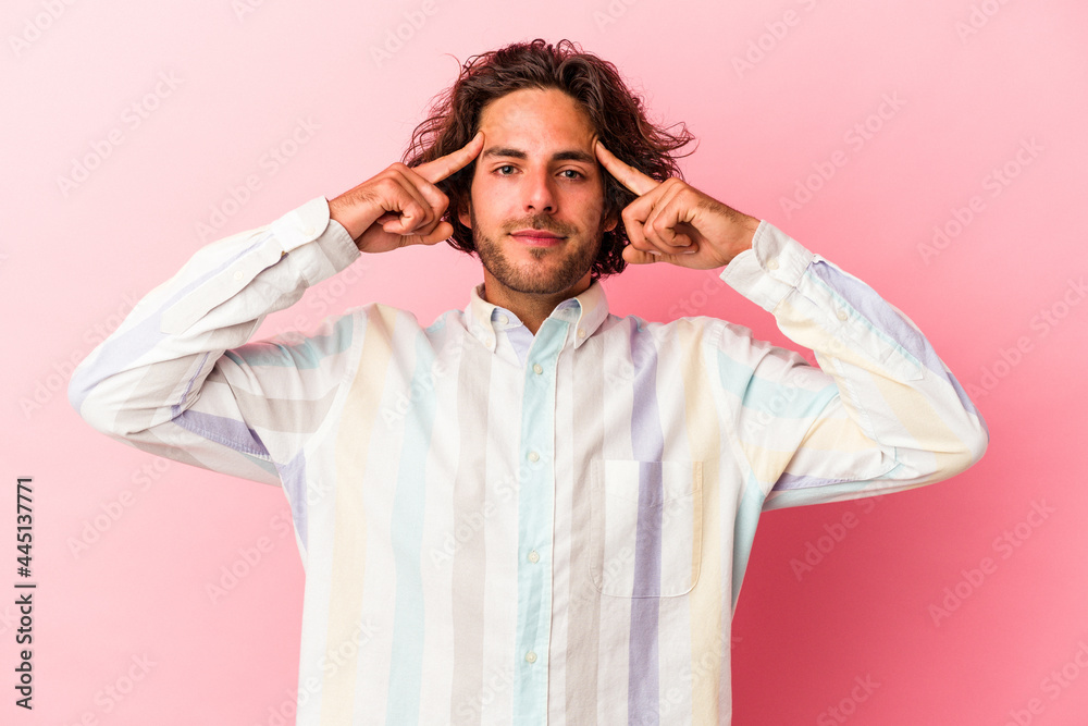 Young caucasian man isolated on pink bakcground focused on a task, keeping forefingers pointing head. Young caucasian man isolated on pink bakcground focused on a task, keeping forefingers pointing head.