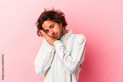 Young caucasian man isolated on pink bakcground yawning showing a tired gesture covering mouth with hand.