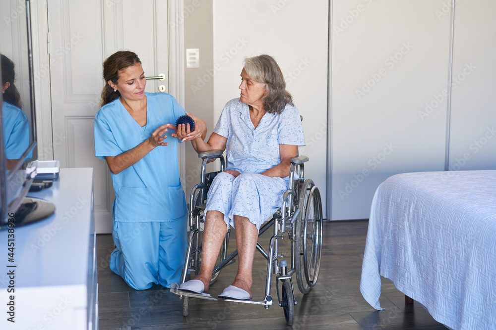 Fototapeta premium Seniorin im Rollstuhl bei der Physiotherapie mit dem Igelball