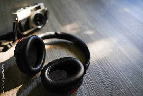 Headphones, and film camera placed on the wood at bedroom in sunset light background. Copy space for your text.