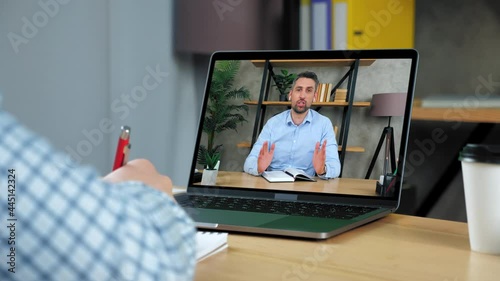 Man business coach in laptop computer screen tells teaches business student. Businessman at home office writes in notebook, study watching video remote education business online course lesson webinar
