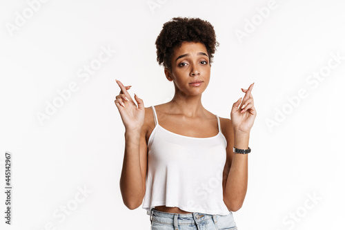 Young black woman in tank top holding fingers crossed for good luck photo