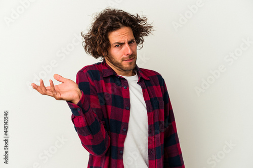 Young caucasian man isolated on white background doubting and shrugging shoulders in questioning gesture.