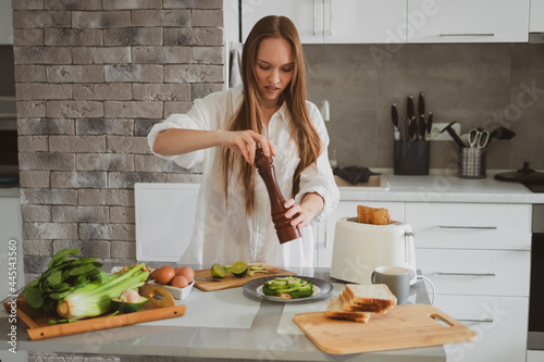 Beautiful young woman in the kitchen at home prepares healthy food