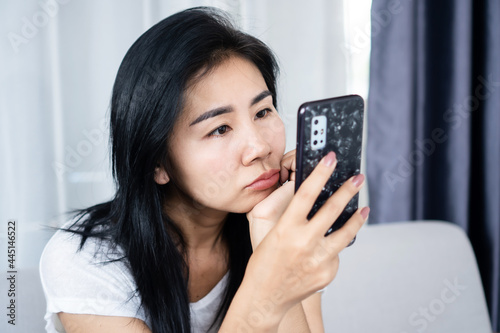 Fotografie Asian woman looking at mobile phone screen too close to the eye, social addictio